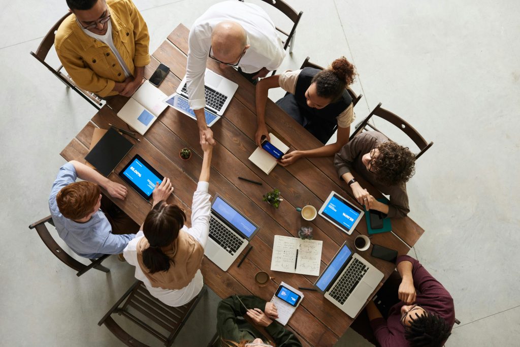 Web Design & Development Top view of a diverse team collaborating in an office setting with laptops and tablets, promoting cooperation.
